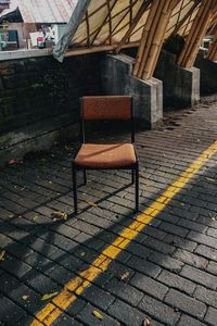 Empty chairs on street amidst buildings in city