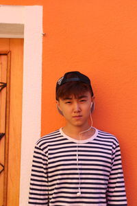 Portrait of boy standing against orange wall