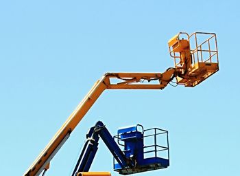 Low angle view of crane against clear blue sky