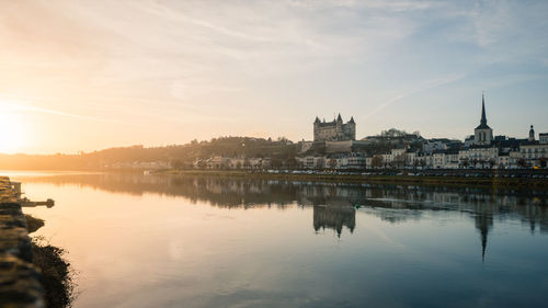 Reflection of buildings in lake at sunset