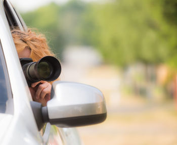 Close-up of woman photographing in car