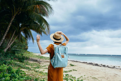 Man wearing hat standing on beach against sky