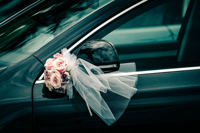 Rose bouquet with veil on side-view mirror of car