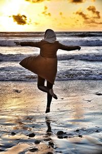 Rear view of woman at beach during sunset