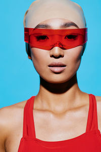 Close-up of woman wearing sunglasses against blue background