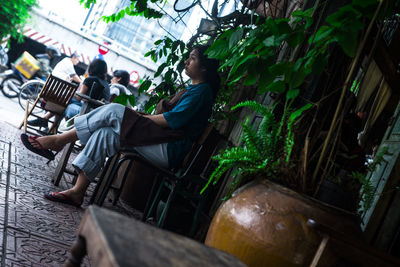 Side view of woman sitting on bench