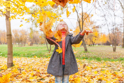 Full length of woman standing on autumn leaves