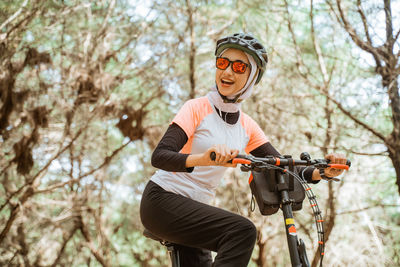 Smiling young woman on bicycle at park