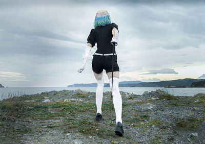 Rear view of man standing by sea against sky