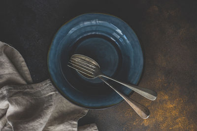 Rustic table setting with empty plate and cutlery set on concrete background with copy space