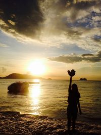 Silhouette man standing at beach against sky during sunset