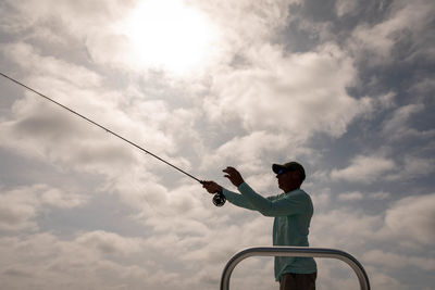 Low angle view of man holding umbrella against sky