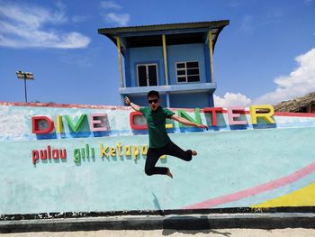 Full length of man jumping in front of built structure