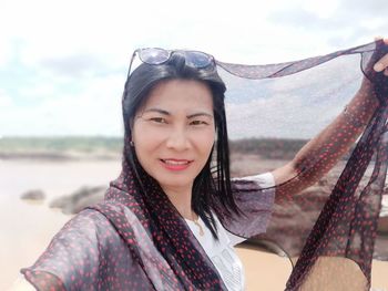 Portrait of smiling woman wearing headscarf against sky