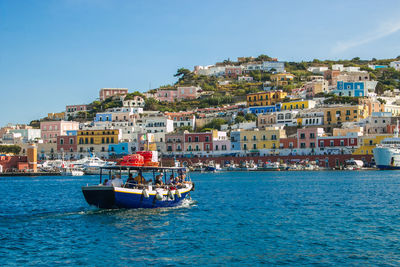 Boats in sea by buildings against clear sky