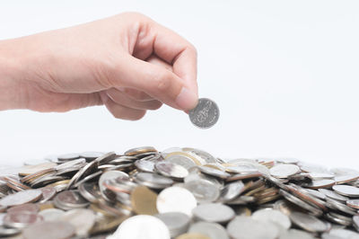 Cropped image of hand holding coins over white background