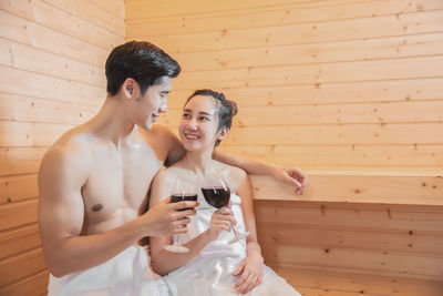 Couple having wine while sitting in sauna