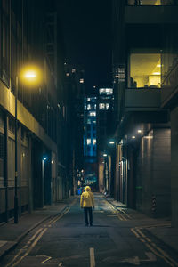 Rear view of woman walking in city at night