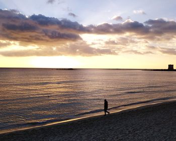 Silhouette person standing on beach against sky during sunset