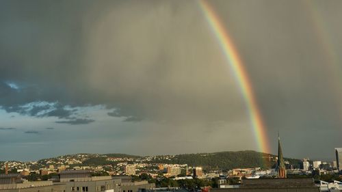 Rainbow over city against sky at night