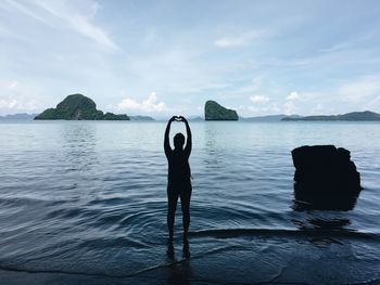 Rear view of person standing in sea against sky