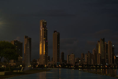 Illuminated buildings in city against sky at night