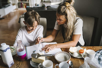 Mother teaching son while having breakfast in living room