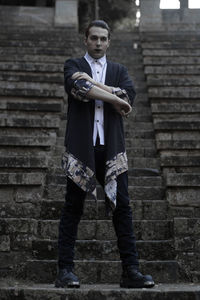 Portrait of young man standing against brick wall