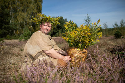 Young woman standing amidst plants against sky