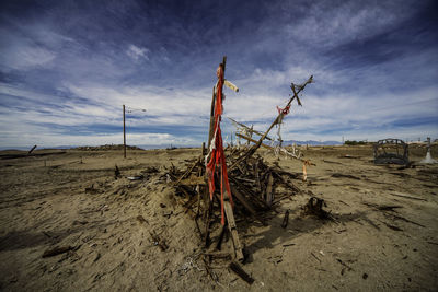 Driftwood on sand at beach against sky