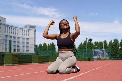African american female athlete feels happy after running long distance on track at sports ground