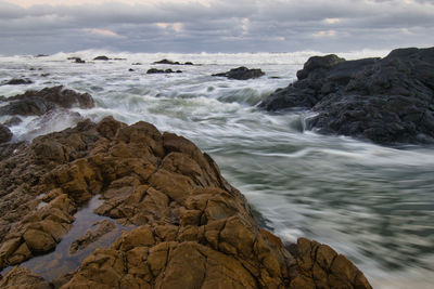 Long exposure view of rocks in sea against sky