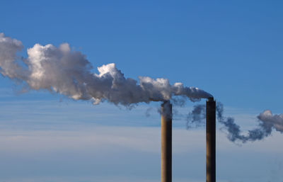 Chimneys emitting smoke against sky