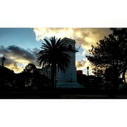 Low angle view of silhouette palm trees against cloudy sky