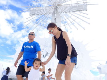 Low angle view of mother and daughter against cross