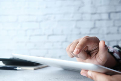 Midsection of person holding smart phone on table