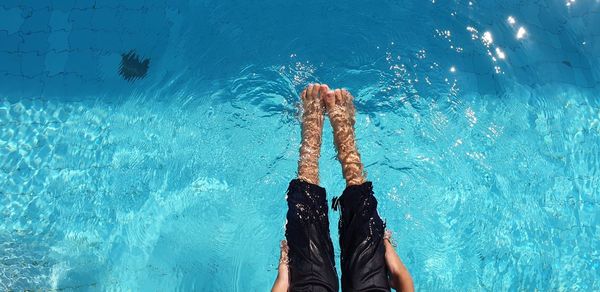 Low section of person standing by swimming pool