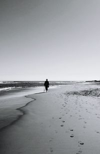 Full length of woman standing on beach against clear sky