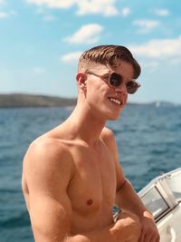 Portrait of shirtless young man against boat in sea