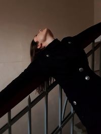 Woman leaning on railing against wall