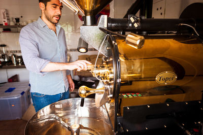 Barista preparing coffee in machinery at cafe