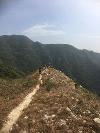 Rear view of people walking on mountain against sky