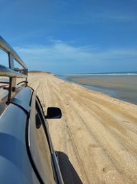 Car on beach against blue sky