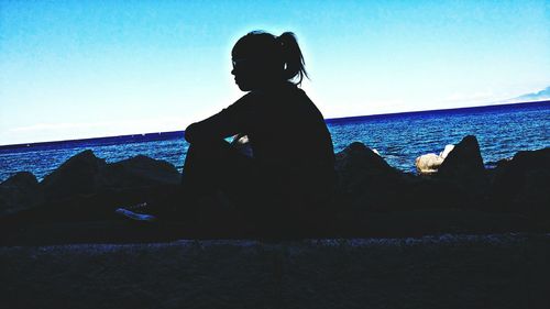 Silhouette woman by sea against clear blue sky