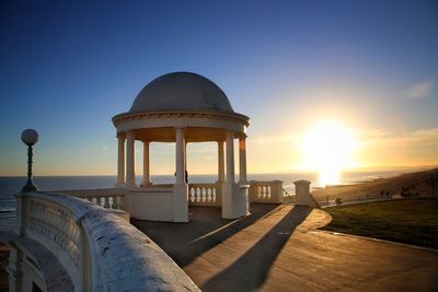 Gazebo in sea against clear sky during sunset