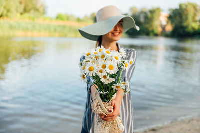 Young woman wearing hat standing by lake