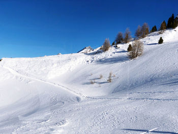 Snow covered landscape against clear blue sky