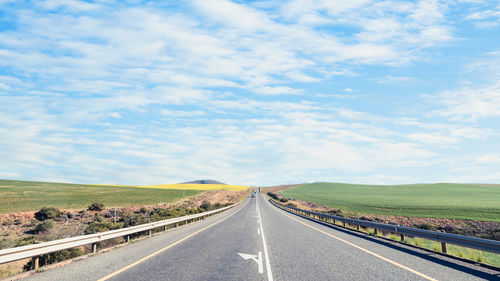 Empty road amidst landscape against sky