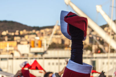 Close-up of hans holding red santa hat against blurred scenery