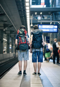 Rear view of people walking in railroad plaform